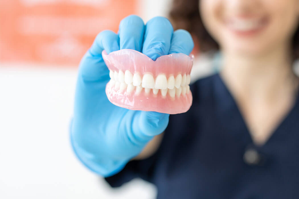 Dentist holding denture in San Antonio, TX