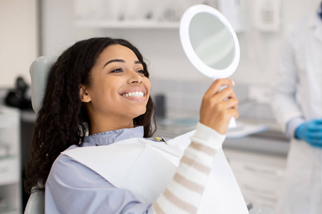 patient looking at a mirror after general dentistry services in San Antonio, TX