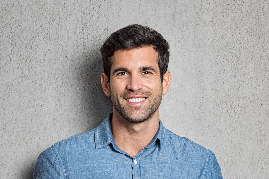 handsome young man smiling against grey textured background