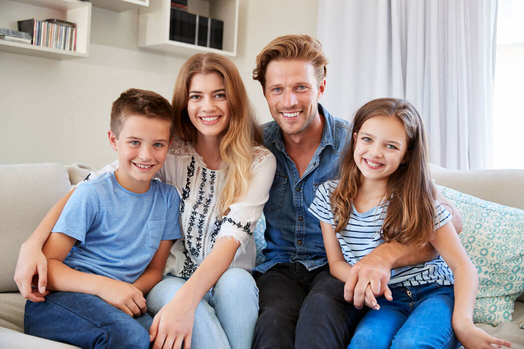 smiling family sitting on a sofa at home together