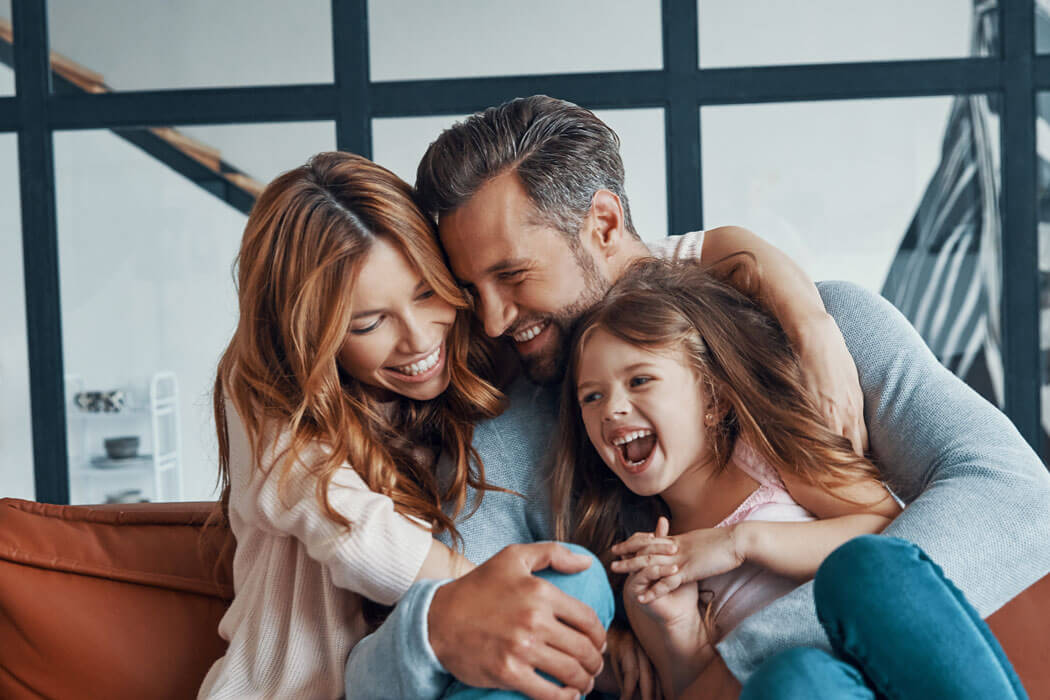 family laughing and smiling on a couch