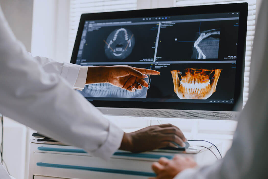 dental professionals examining digital X-ray images on a computer for diagnosis and treatment planning